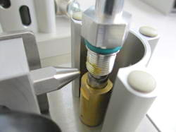 Manual greasing device for greasing small components. Close-up view of the area to be greased. The spraying process starts automatically when a part is inserted.